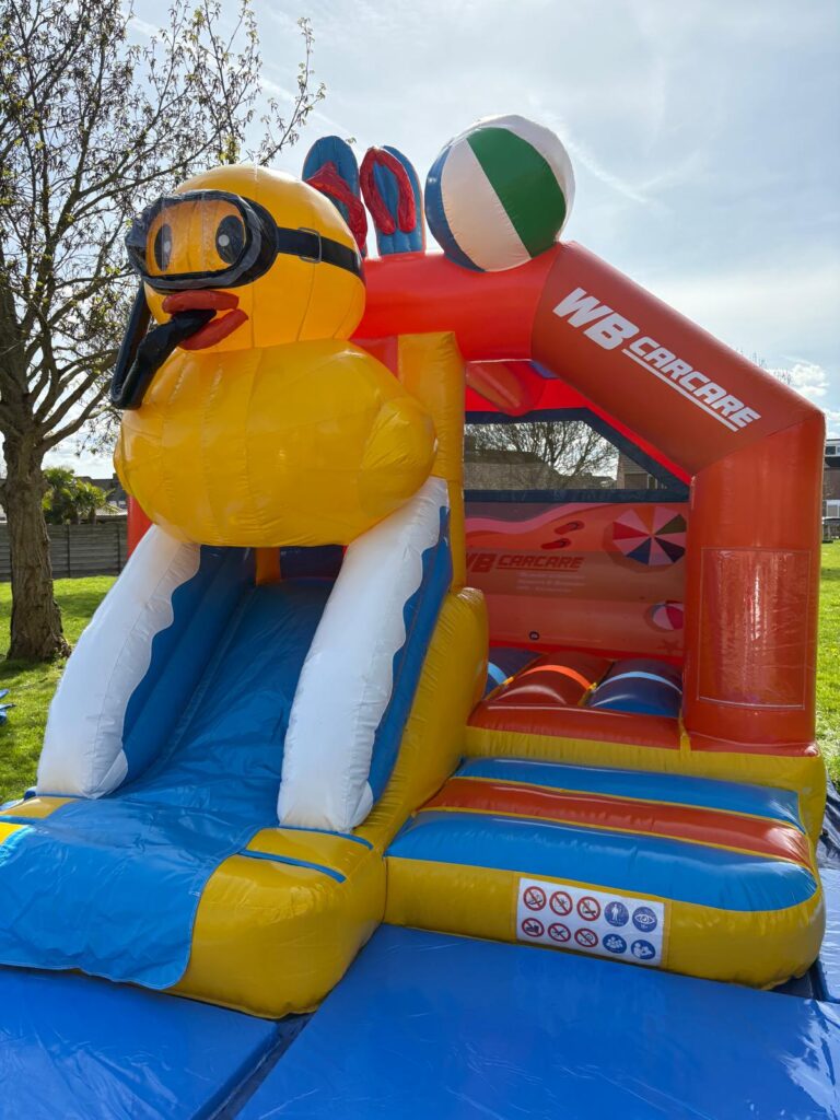 Kinderen kijken naar de badeend springkussen met glijbaan
