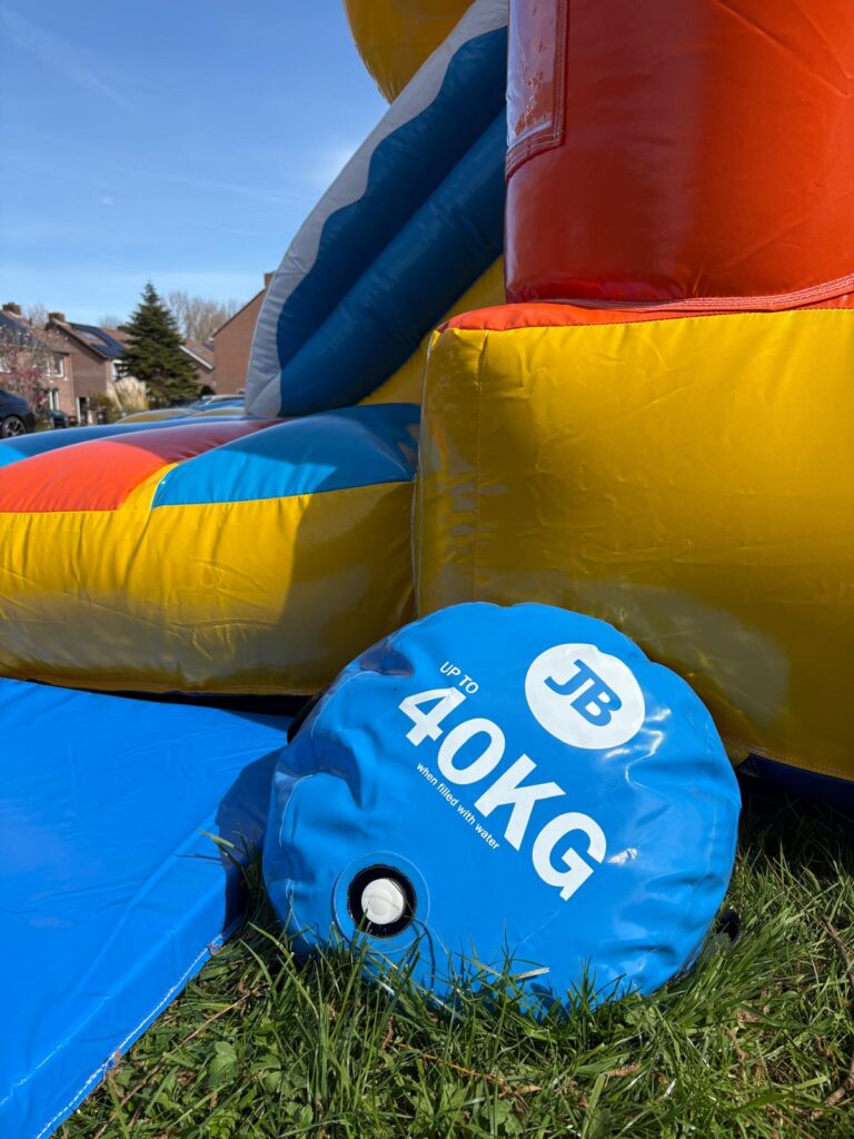 Blauwe verankeringszak van 40 kilo naast het springkussen